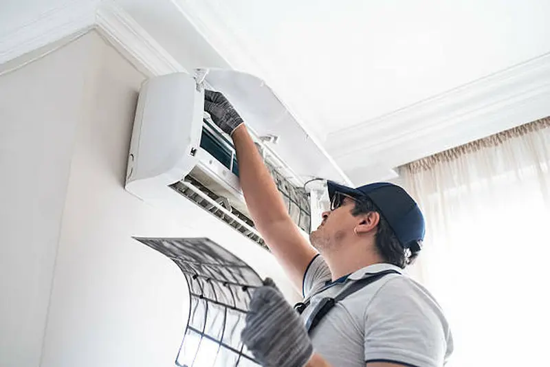 A professional cleaner from The Kleeners performing precise AC filter maintenance to ensure a clean and welcoming indoor environment for home and business clients